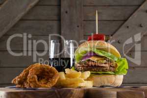Hamburger, onion ring and french fries with cold drink on chopping board