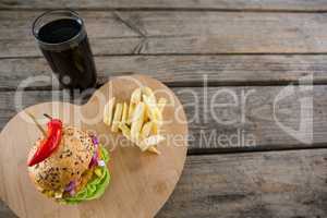 Burger with French fries on cutting board by drink