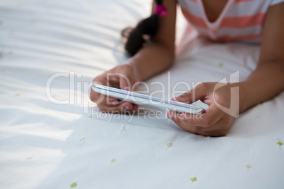 Midsection of girl using mobile phone on bed