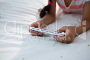 Midsection of girl using mobile phone on bed