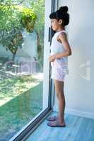 Side view of girl looking through window