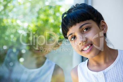 Close-up portrait of girl leaning on window glass