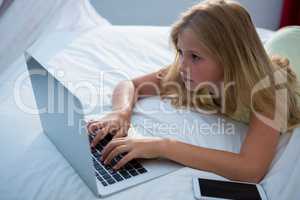 Girl using laptop on bed