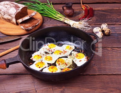 Fried quail eggs in a black cast-iron frying pan
