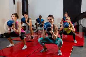 Young athletes crouching with exercise balls