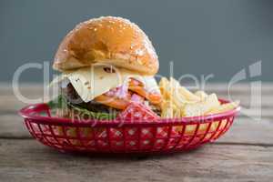 Cheeseburger and French fries in basket against wall