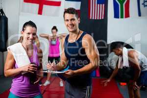 Portrait of young male and female athletes discussing with clipboard