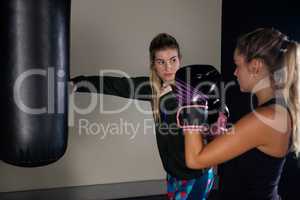 Trainer assisting woman in boxing