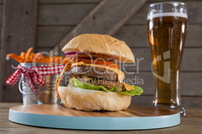 Hamburger, french fries and glass of beer on table