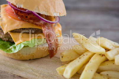Burger with French fries served on cutting board