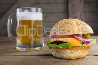 Burger with glass of beer on wooden table