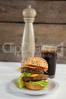 Close-up of hamburger in plate with glass of cold drink
