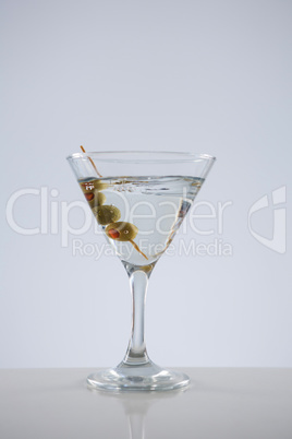 Cocktail martini with olives on table