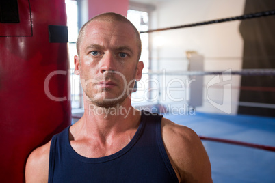 Close-up portrait of young male athlete standing against boxing ring