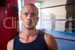 Close-up portrait of young male athlete standing against boxing ring