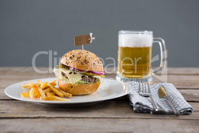 Hamburger with fries served in plate by beer glass