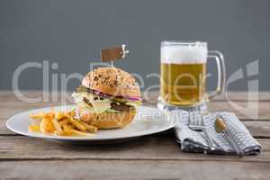Hamburger with fries served in plate by beer glass