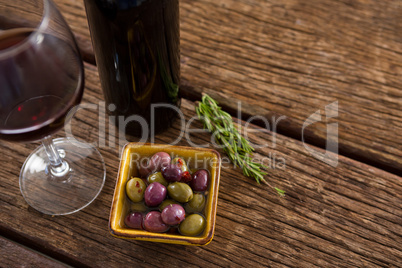 Close-up of marinated olives with glass of wine