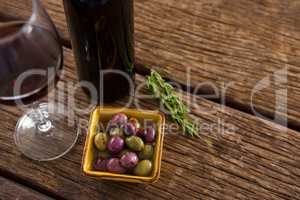 Close-up of marinated olives with glass of wine