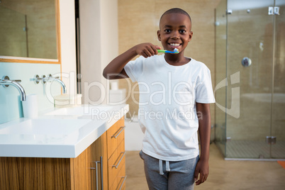 Portrait of smiling boy with toothbrush by sink