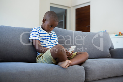 Boy using mobile phone sitting on sofa at home