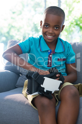 Portrait of smiling boy adjusting virtual reality headset at home