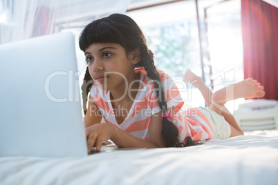Tilt shot of girl using laptop on bed