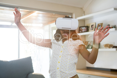 Cheerful girl wearing virtual reality simulator while standing in living room