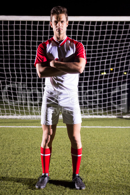 Portrait of confident male soccer player standing with arms crossed