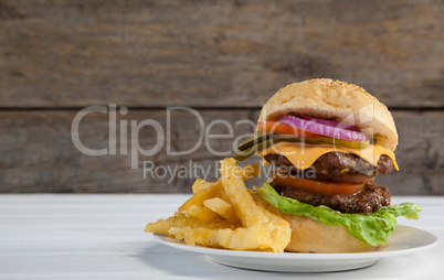 Hamburger and french fries in plate on wooden table