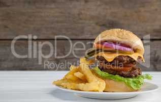Hamburger and french fries in plate on wooden table