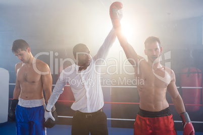 Referee lighting hand of winner in boxing ring