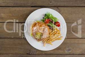 Hamburger, french fries and salad in plate on wooden table