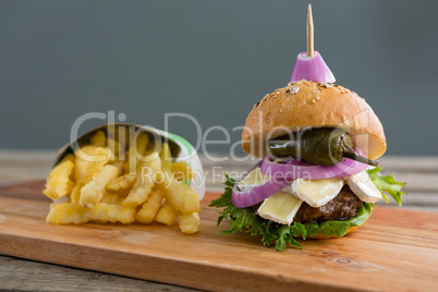 Burger by French fries in box on cutting board
