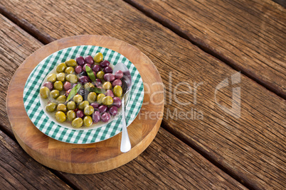 Marinated olives with herbs on wooden board