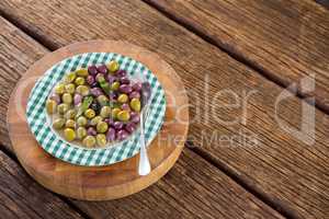 Marinated olives with herbs on wooden board