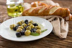 Marinated olives with olive oil and breakfast on wooden table