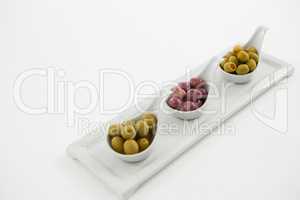 Various types of olives in spoon on serving tray