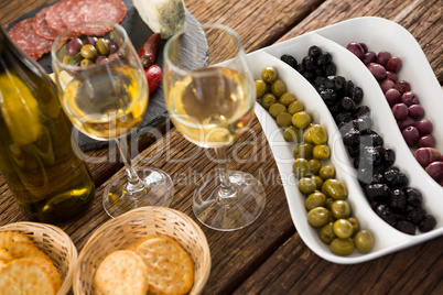 Close-up of marinated olives with bottle of wine and food