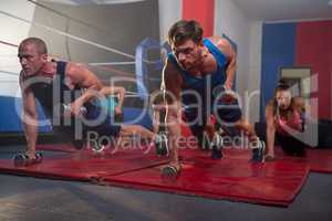 Young athletes exercising with dumbbells by boxing ring
