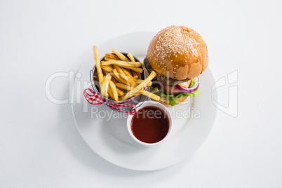 Burger by french fries in container with tomato sauce