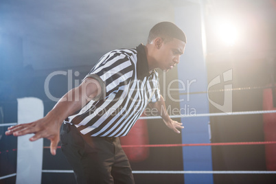 Young male referee showing hand sign in boxing ring