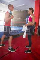 Side view of young male and female athletes talking by boxing ring