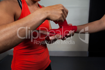 Trainer tying hand wrap on woman hand
