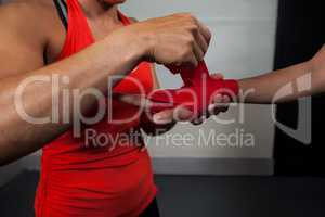 Trainer tying hand wrap on woman hand