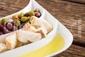 Marinated olives, bread pieces and olive oil in platter