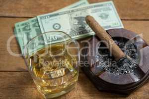 High angle view of whisky and cigar by paper currency
