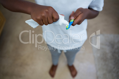 Low section of boy removing toothpaste on brush