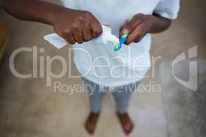 Low section of boy removing toothpaste on brush