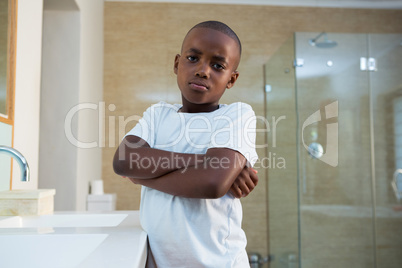 Portrait of boy standing by sink with arms crossed